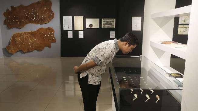 Pengunjung menyaksikan artefak, lukisan, foto, maupun naskah kuno yang dipamerkan dalam pameran terkait Perjanjian Breda yang melibatkan Pulau Banda, di Galeri Nasional, Jakarta, Rabu (20/9/2017). [Suara.com/Kurniawan Mas'ud]