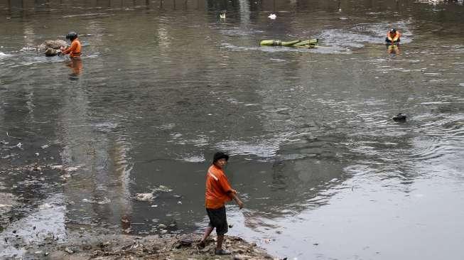 Petugas PPSU tampak bertugas membersihkan tumpukan sampah di Sungai Ciliwung saat debit air menyusut akibat kemarau di kawasan Bukit Duri, Jakarta, Selasa (19/9/2017). [Suara.com/Kurniawan Mas'ud]