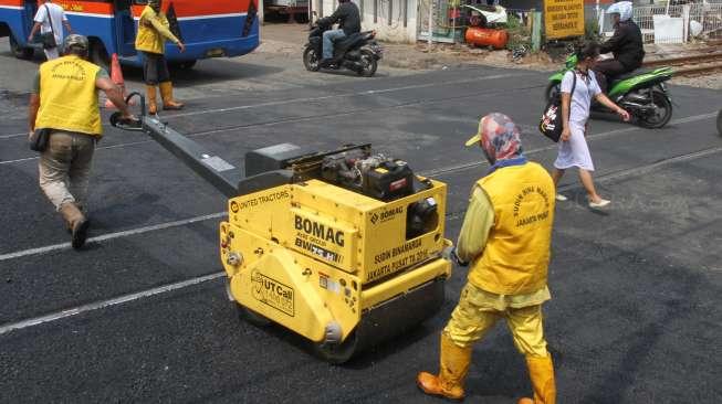 Petugas Sudin Binamarga Jakarta Pusat melakukan perbaikan jalan di perlintasan kereta api di Manggarai, Jakarta, Senin (25/9).