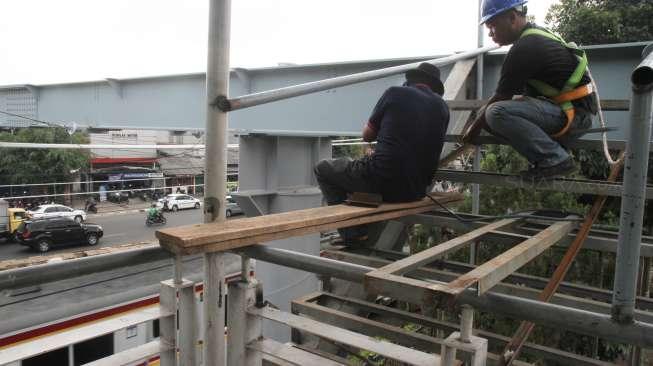 Pekerja menyelesaikan pembangunan jembatan penyeberangan orang (JPO) di sekitar Stasiun Tanjung Barat, Jakarta, Jumat (29/9).