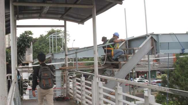 Pekerja menyelesaikan pembangunan jembatan penyeberangan orang (JPO) di sekitar Stasiun Tanjung Barat, Jakarta, Jumat (29/9).