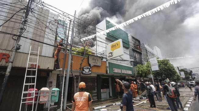 Petugas dari Suku Dinas Pemadam Kebakaran Jakarta Pusat berusaha memadamkan api yang membakar sejumlah ruko di Jalan Sabang, Jakarta, Minggu (8/10). [Suara.com/Kurniawan Mas'ud]