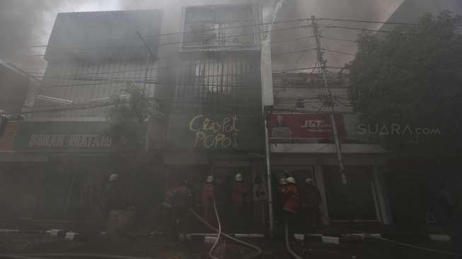 Petugas dari Suku Dinas Pemadam Kebakaran Jakarta Pusat berusaha memadamkan api yang membakar sejumlah ruko di Jalan Sabang, Jakarta, Minggu (8/10). [Suara.com/Kurniawan Mas'ud]