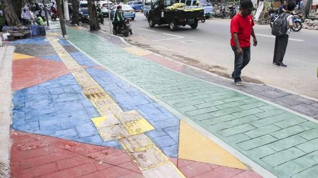 Pekerja menyelesaikan pengecatan trotoar dengan warna bervariasi di Jalan AM Sangaji, Jakarta, Selasa (10/10).
