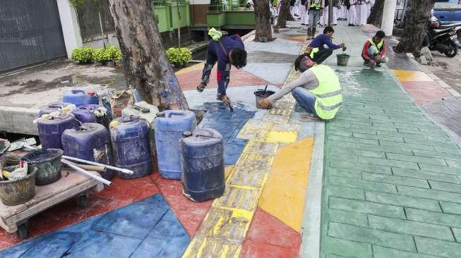 Pekerja menyelesaikan pengecatan trotoar dengan warna bervariasi di Jalan AM Sangaji, Jakarta, Selasa (10/10).