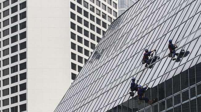 Pekerja membersihkan kaca gedung perkantoran di Jakarta, Rabu (11/10).