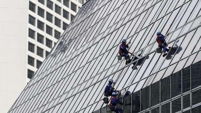 Pekerja membersihkan kaca gedung perkantoran di Jakarta, Rabu (11/10).