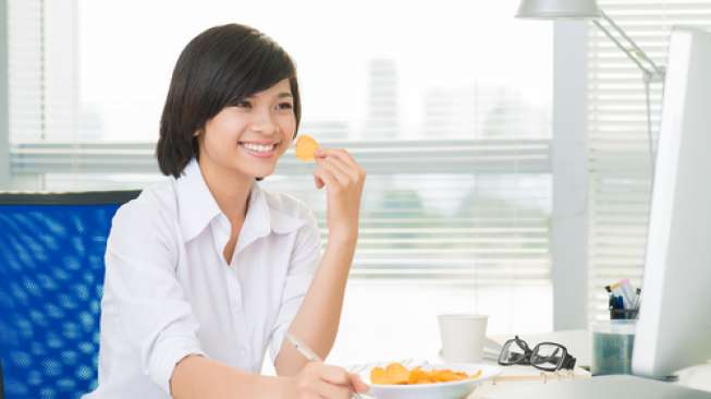 Ilustrasi mengemil atau menyantap makanan ringan di kantor. (Shutterstock)