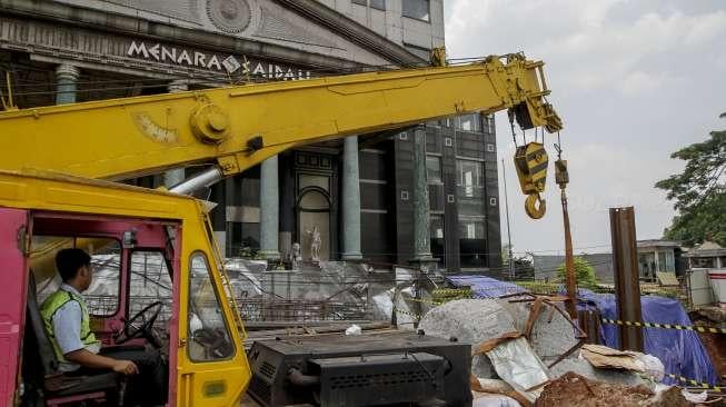 Pekerja LRT memasang terpal plastik untuk menutup area bekas amblas di depan gedung Menara Saidah, Jalan MT. Haryono, Jakarta, Jumat (13/10).