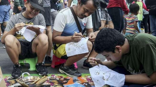 Sejumlah pengunjung car free day (CFD) terlihat belajar cara membuat batik di kawasan Bundaran HI, Jakarta, Minggu (22/10/2017). [Suara.com/Kurniawan Mas'ud]