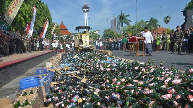 Sejumlah santri menyaksikan petugas dengan alat berat menghancurkan ribuan botol minuman keras di alun-alun Kudus, Jawa Tengah, Minggu (22/10/2017), saat peringatan Hari Santri Nasional. [Antara/Yusuf Nugroho]