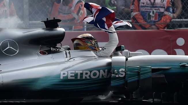 Pebalap Mercedes asal Inggris, Lewis Hamilton, merayakan capaian Juara Dunia Formula 1 (F1) musim 2017 di mobilnya, usai finis di posisi kesembilan di Sirkuit Hermanos Rodriguez, GP Meksiko, Minggu (29/10/2017) waktu setempat. [Yuri Cortez/AFP]