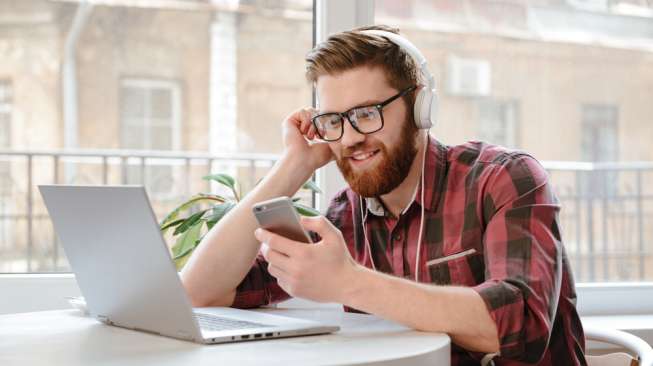 Lelaki sedang mendengarkan musik sambil bekerja. [Shutterstock]