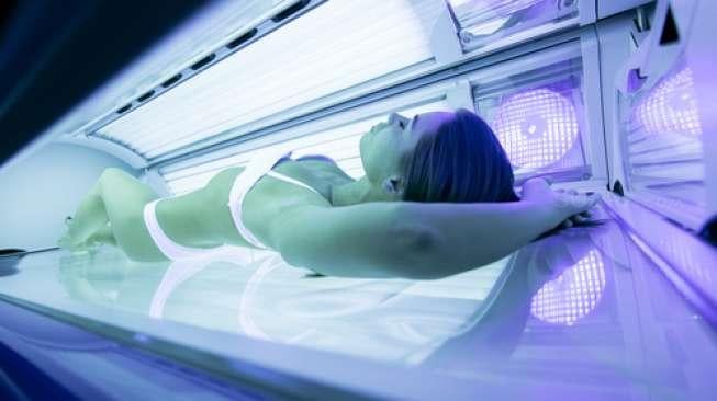 Ilustrasi seorang perempuan berjemur di bawah sunbeds (Shutterstock)