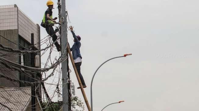 Beberapa petugas tampak bekerja memperbaiki jaringan utilitas kabel PLN dan Penerangan Jalan Umum (PJU) di kawasan Kampung Melayu Kecil, Jakarta, Rabu (8/11/2017). [Suara.com/Kurniawan Mas'ud]