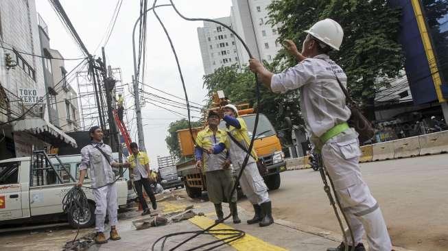 Sejumlah petugas terlihat bekerja memperbaiki jaringan utilitas kabel PLN dan Penerangan Jalan Umum (PJU) di kawasan Kampung Melayu Kecil, Jakarta, Rabu (8/11/2017). [Suara.com/Kurniawan Mas'ud]