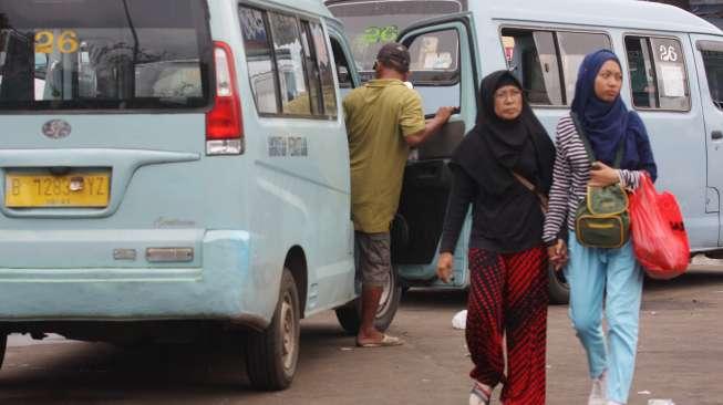 Sejumlah warga terlihat berjalan di sela-sela angkot yang sedang menunggu penumpang di Terminal Kampung Melayu, Jakarta Timur, Sabtu (11/11/2017). [Suara.com/Oke Atmaja]