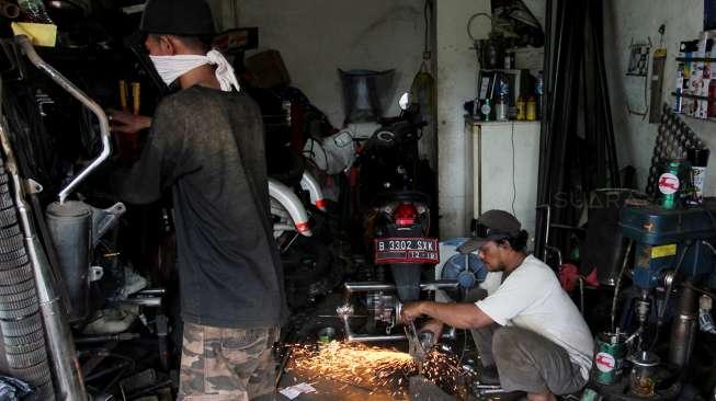 Catur Bambang, pemilik bengkel Modifikasi Motor Roda 3 khusus difabel saat memodifikasi sepeda motor pesanan pelanggan di bengkel miliknya, di kawasan Bintaro, Sabtu (11/11/2017). [Suara.com/Oke Atmaja]