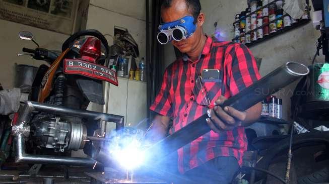 Catur Bambang, pemilik bengkel Modifikasi Motor Roda 3 khusus difabel saat melakukan modifikasi sepeda motor pesanan pelanggan di bengkel miliknya, di kawasan Bintaro, Sabtu (11/11/2017). [Suara.com/Oke Atmaja]