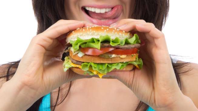 Ilustrasi seorang perempuan menikmati burger. [Shutterstock]