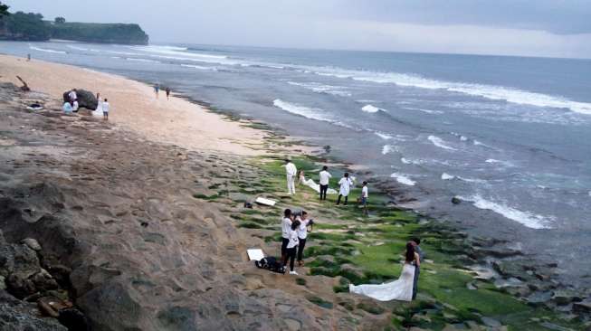 Sejumlah pasangan berbusana pengantin sedang berfoto di pantai dan tebing Balangan, Jimbaran, Kuta Selatan, Bali pada Rabu (22/11). [Suara.com/Liberty Jemadu]