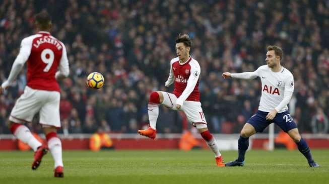 Pemain Arsenal Mesut Ozil (tengah) melewati pemain Tottenham Hotspur [AFP]