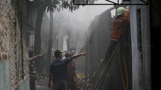 Petugas berusaha memamdamkan sisa api yang membakar sebuah pabrik dan gudang kosmetik di kawasan Tambora, Jakarta, Senin (4/12).