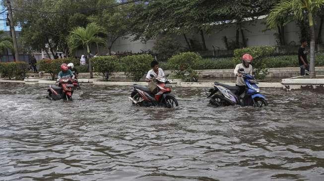 Warga melintasi banjir rob yang menggenangi kawasan Muara Baru, Jakarta, Selasa (5/12).