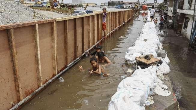 Warga melintasi banjir rob yang menggenangi kawasan Muara Baru, Jakarta, Selasa (5/12).