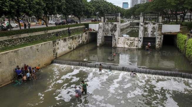 Sejumlah warga berebut mencari ikan di kali kawasan Epicentrum, Kuningan, Jakarta, Rabu (13/12).