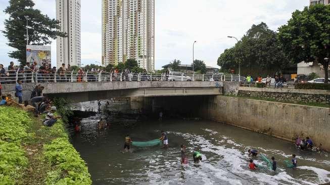 Sejumlah warga berebut mencari ikan di kali kawasan Epicentrum, Kuningan, Jakarta, Rabu (13/12).