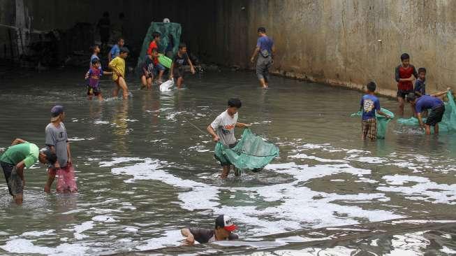 Sejumlah warga berebut mencari ikan di kali kawasan Epicentrum, Kuningan, Jakarta, Rabu (13/12).