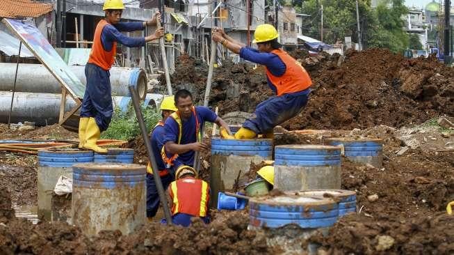 Pekerja memperbaiki saluran pipa air bersih milik PDAM yang bocor di kawasan proyek Jalan Layang Tol Becakayu, Jakarta, Jumat (15/12).