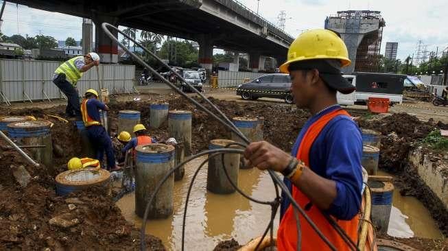 Pekerja memperbaiki saluran pipa air bersih milik PDAM yang bocor di kawasan proyek Jalan Layang Tol Becakayu, Jakarta, Jumat (15/12).