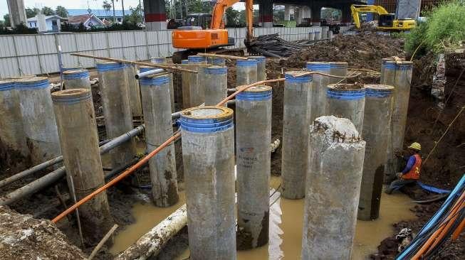 Pekerja memperbaiki saluran pipa air bersih milik PDAM yang bocor di kawasan proyek Jalan Layang Tol Becakayu, Jakarta, Jumat (15/12).