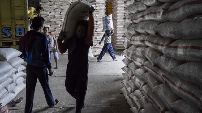 Buruh angkut beraktivitas mengangkut karung beras ke dalam gudang penyimpanan di Pasar Induk Beras Cipinang (PIBC), Jakarta, Rabu (20/12/2017). [Suara.com/Kurniawan Mas'ud]