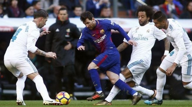 Pemain Barcelona Lionel Messi (tengah) melewati tiga pemain Real Madrid [AFP]