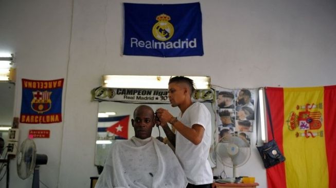 Seorang fans Madrid serius menyaksikan el Clasico di tempat pangkas rambut [AFP]