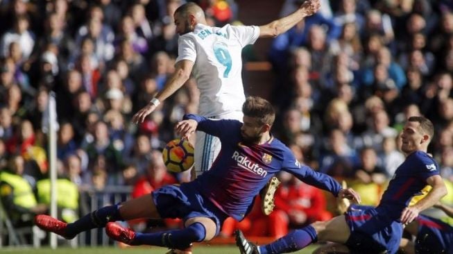 Pemain Barcelona Gerard Pique menghentikan laju pemain Madrid Karim Benzema [AFP]