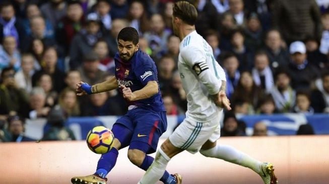 Pemain Barcelona Luis Suarez mencoba mengatasi kawalan ketat pemain Real Madrid Sergio Ramos [AFP]