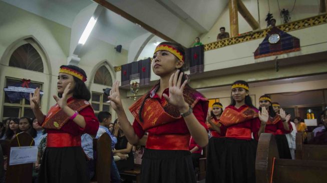 Sejumlah gadis mengenakan ulos dan menari tortor saat Misa Malam Natal di Gereja Santa Maria A. Fatima di Kota Pekanbaru, Riau, Minggu (24/12). 