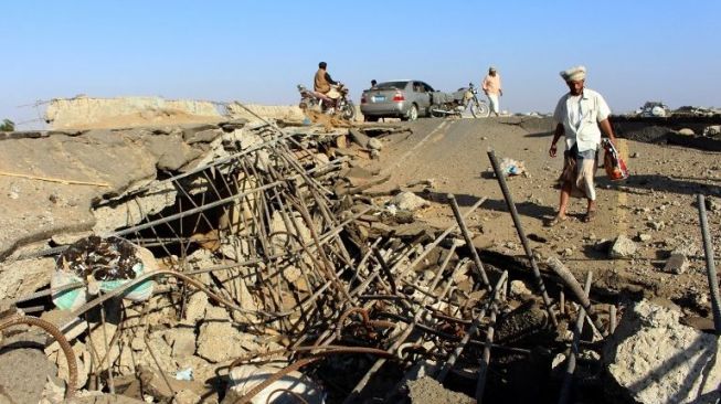 Seorang warga tampak tengah melihat kerusakan yang ditimbulkan serangan udara koalisi Arab Saudi pada jembatan penghubung antara area Abbas dan Harad di utara Provinsi Hajjah, Yaman, Senin (25/12/2017). [AFP]