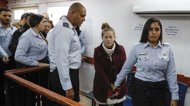 Ahed Tamimi, gadis Palestina berusia 16 tahun saat digiring oleh polisi Israel ke ruang persidangan, Kamis (28/12/2017). Ahed Tamimi menjadi ikon perlawanan Palestina terhadap penjajahan Israel. [Ahmad Gharabli/AFP]