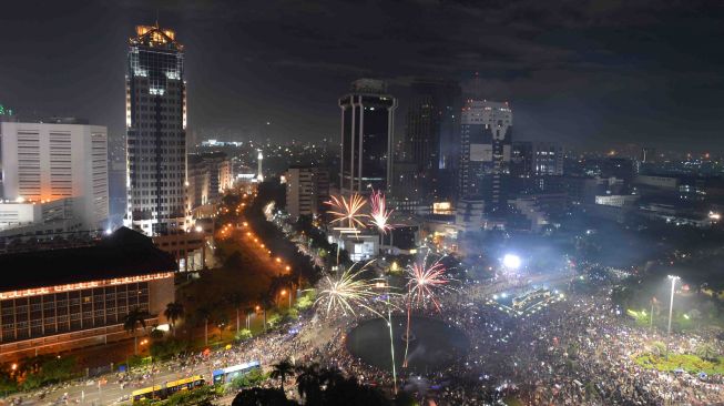 Suasana pesta kembang api pada malam tahun baru 2018 di kawasan Bundaran Patung Kuda, Jakarta Pusat, Minggu (31/12).