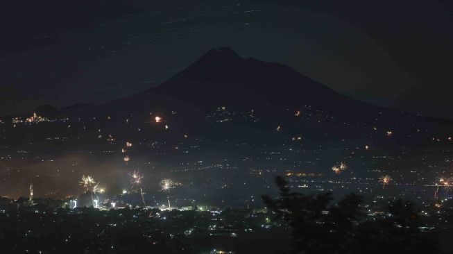 Warga menerbangkan lampion dengan latar belakang Gunung Merapi di Prambanan, Sleman, DI Yogyakarta, Senin (1/1).