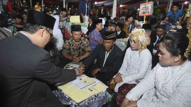 Sejumlah pasangan pengantin mengikuti nilkah massal di Thamrin Park ride, Jakarta, Minggu (31/12).