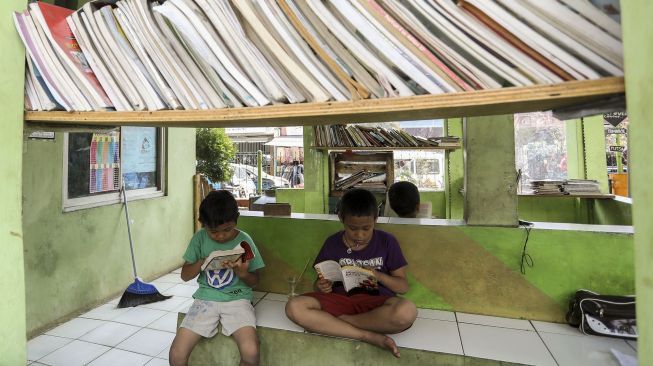 Sejumlah anak terlihat asyik membaca buku di Taman Baca Kolong Flyover Ciputat, Tangerang Selatan, Provinsi Banten, Kamis (4/1/2018). [Suara.com/Kurniawan Mas'ud]