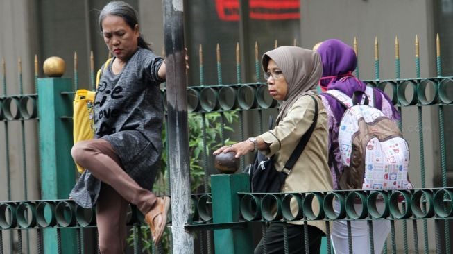 Sejumlah penumpang melompati pagar pembatas di Stasiun Cikini, Jakarta, Senin (8/1). 