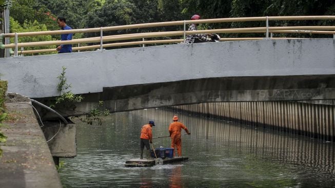 Petugas Penanganan Sarana dan Prasarana Umum (PPSU) DKI Jakarta membersihkan aliran sungai di kawasan Kebon Sirih, Jakarta, Selasa (9/1). 