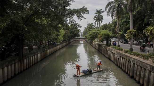 Petugas Penanganan Sarana dan Prasarana Umum (PPSU) DKI Jakarta membersihkan aliran sungai di kawasan Kebon Sirih, Jakarta, Selasa (9/1). 